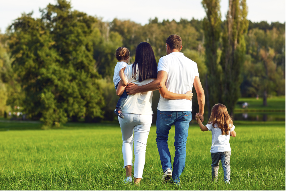 Family walking together through a green park, symbolizing hope, stability, and building a healthy future after addiction recovery.